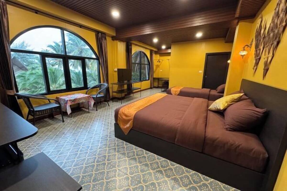 Une chambre avec une grande fenêtre, un lit, un bureau et une chaise.