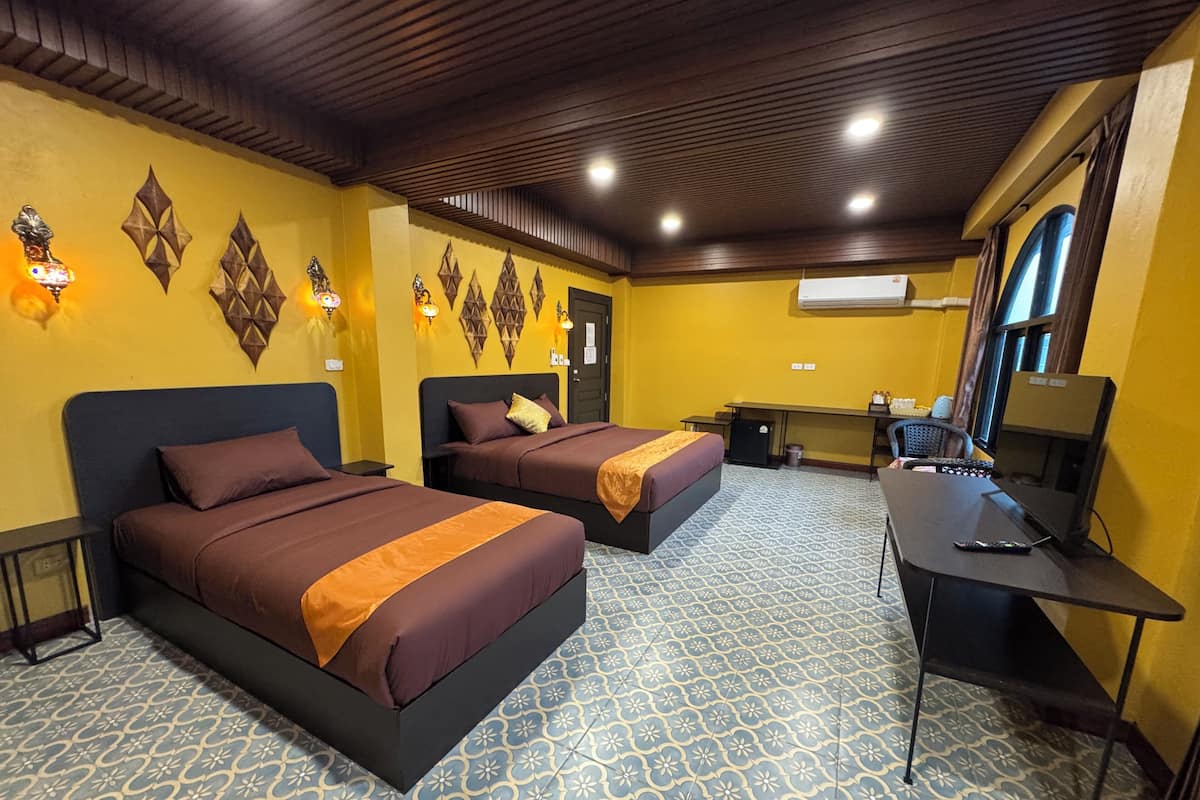 Une chambre d’hôtel avec deux lits, un bureau, un ordinateur et une petite kitchenette.