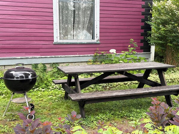 A wooden picnic table and a barbecue grill in front of a house with a window. - Private Tavern, 3 bedrooms, WiFi & AC within an 1800's Victorian (Worcester)