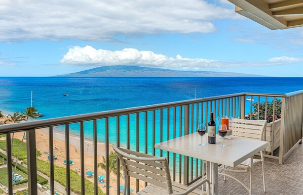 Un balcon avec une table, des chaises et une vue sur lâocĂ©an et la plage.