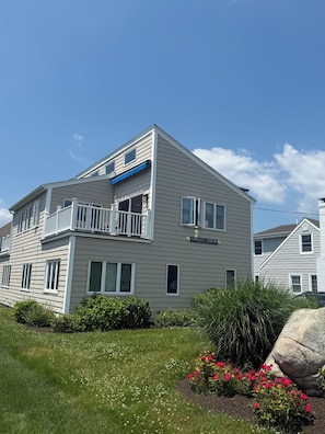 A two-story building with a balcony, a sign reading 'Sunny View,' and a well-maintained lawn with flowers. - Oceanview, 5-bedroom, 2.5-ba, Overlooking South Beach, Dogs Welcome in GLP (Groton)