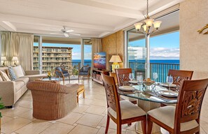 A spacious living area with a balcony, a dining table set for four, and a television.