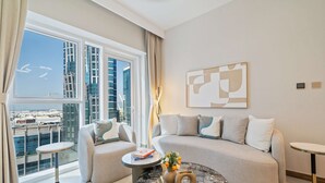 A modern living room with a sofa, two side tables, a coffee table, and a large window offering a city view.