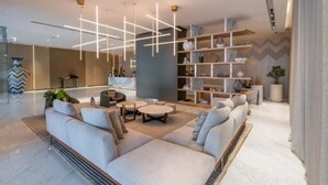 A modern living room with a sectional sofa, round coffee table, and a bookshelf.