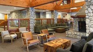 A spacious lobby with wooden beams, stone walls, and a fireplace. There are multiple seating areas with sofas and chairs. - Modern Air-Conditioned Ski In/Out 1 BR: Sleeps 4, King bed, Hot Tub, Pool! (Whistler)