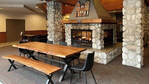 A stone fireplace with a wooden mantel and a built-in seating area. - Modern Air-Conditioned Ski In/Out 1 BR: Sleeps 4, King bed, Hot Tub, Pool! (Whistler)