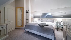 A bedroom with a bed, bedside tables, a mirror, and a door.