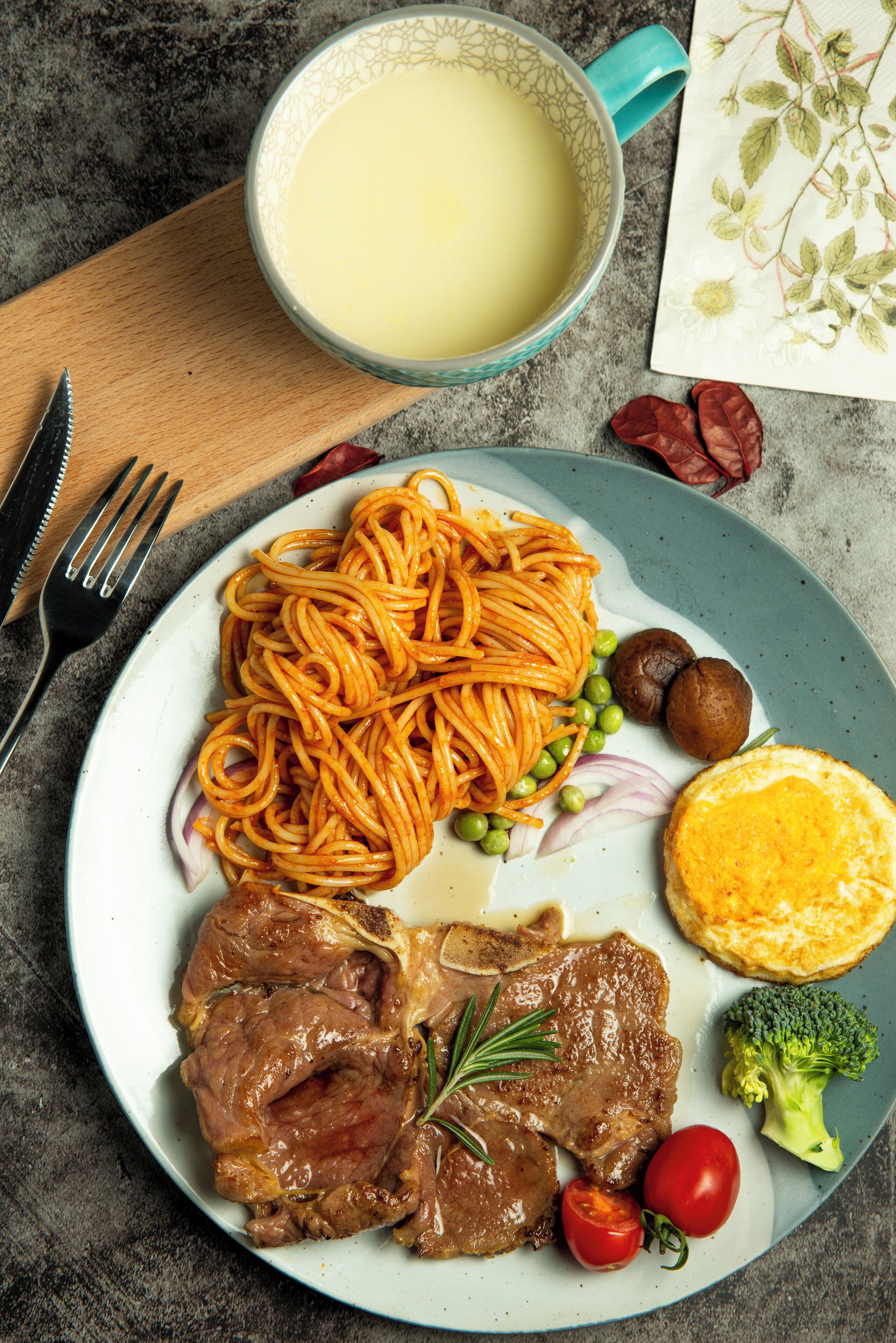 A plate with spaghetti, meat, vegetables, and a cup of milk.