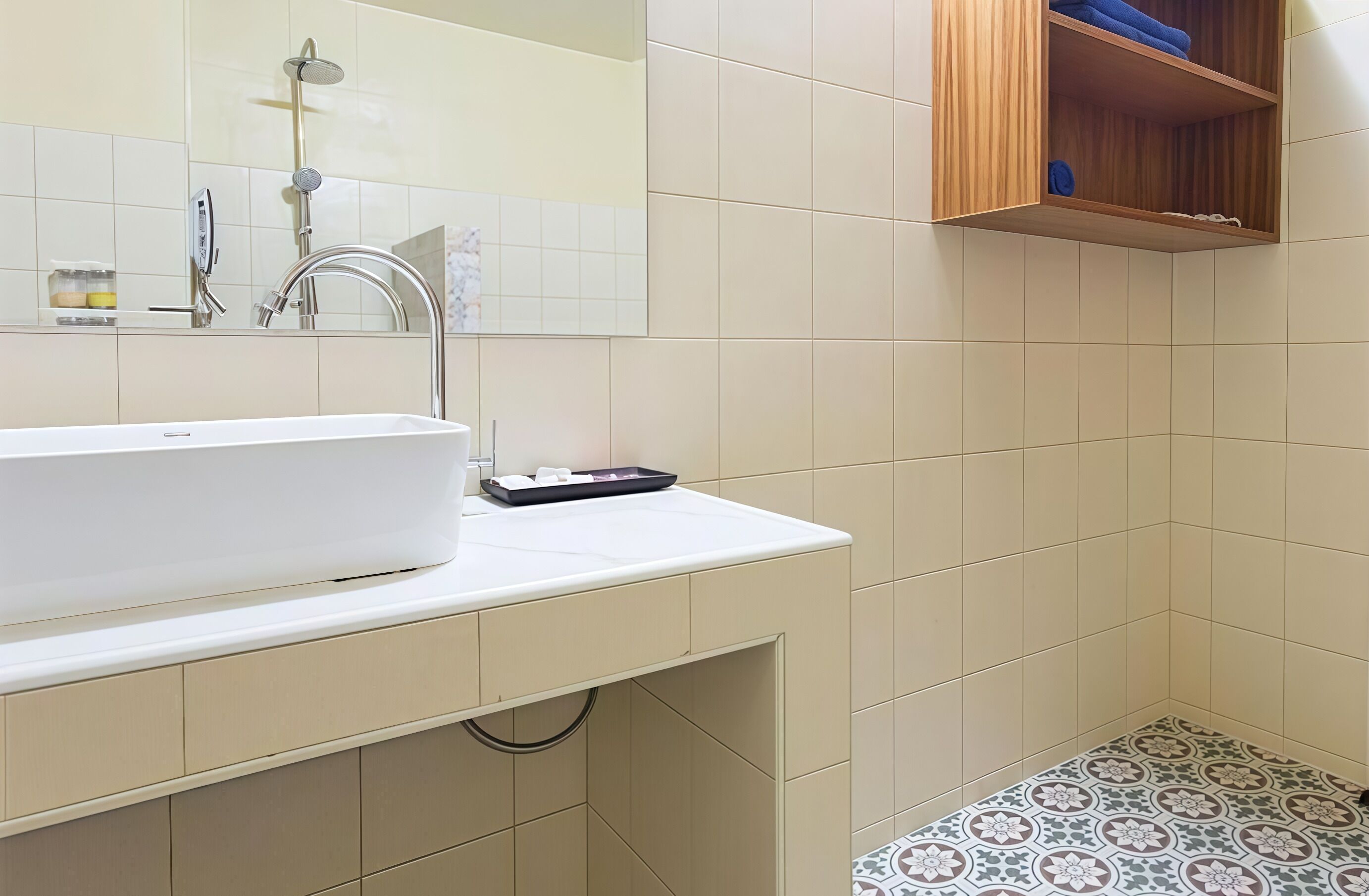 A bathroom with a white sink, a handheld showerhead, and a wooden shelf above the toilet.