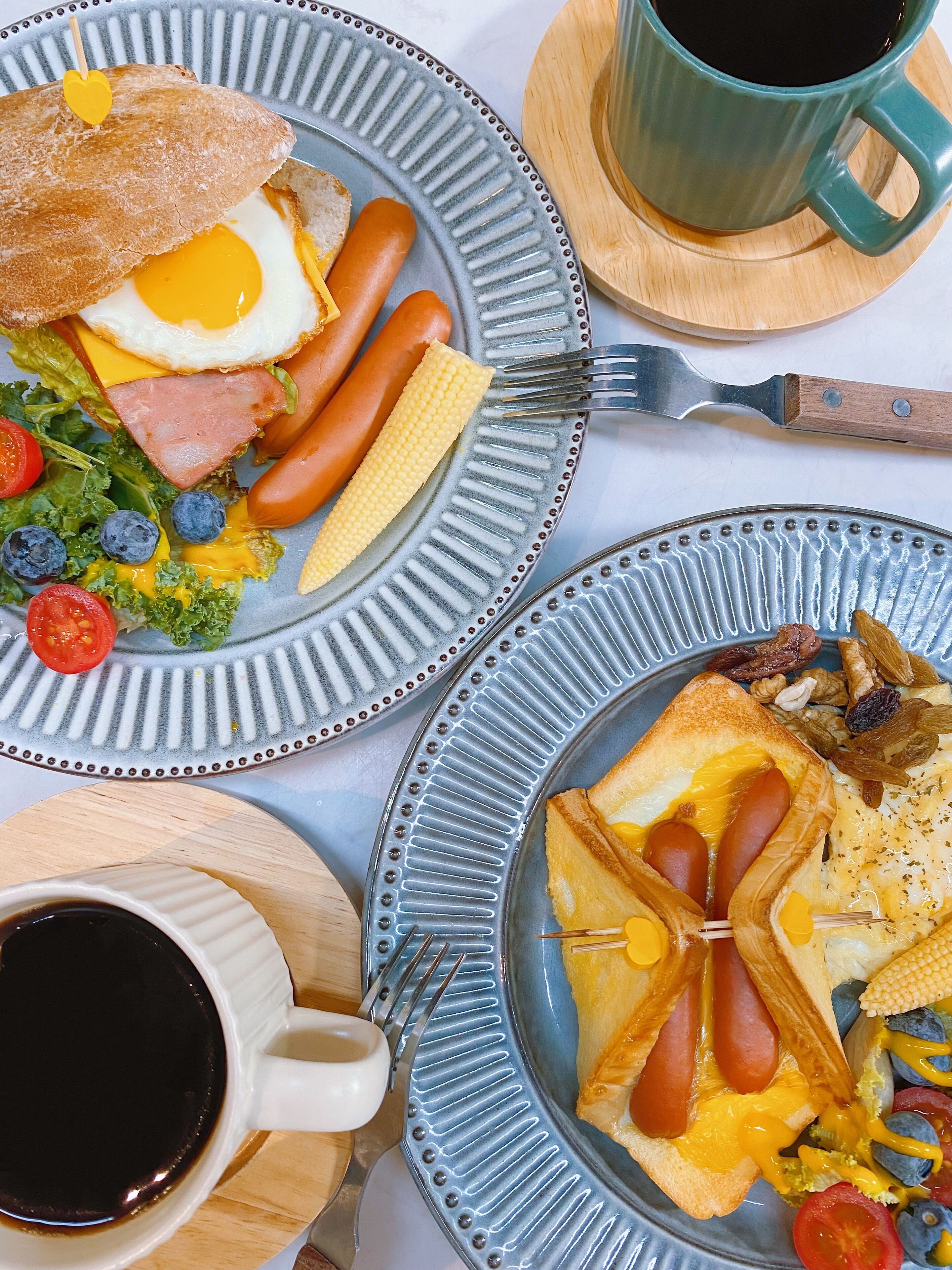A breakfast setting with plates of food, a cup of coffee, and a knife on a table.