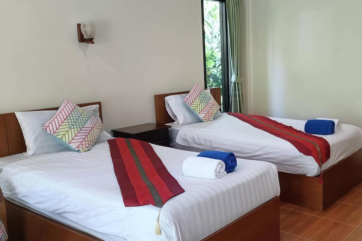 Two single beds with wooden headboards, white bedding, and colorful pillows.