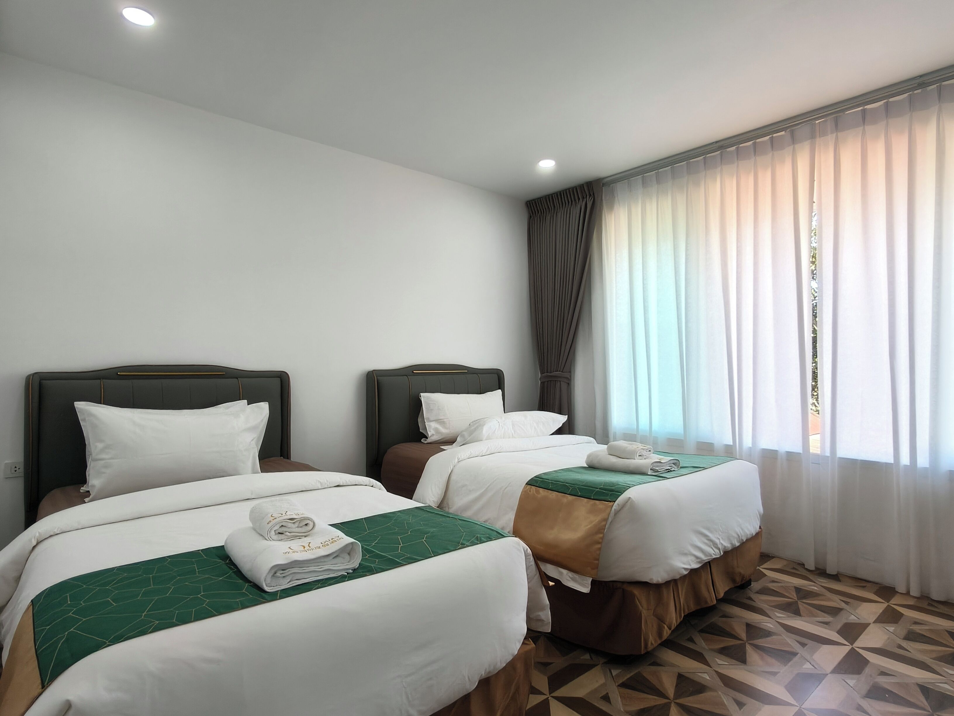 Una habitación de hotel con dos camas, una ventana con cortinas y un piso estampado.