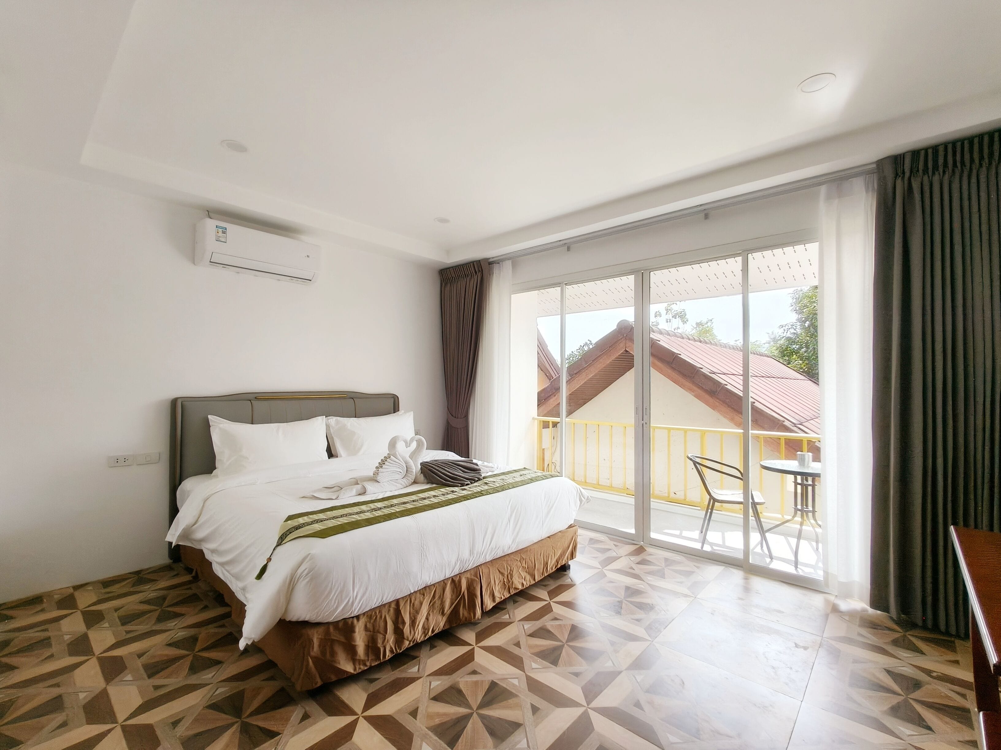 A hotel room with a bed, a large window, and a balcony.