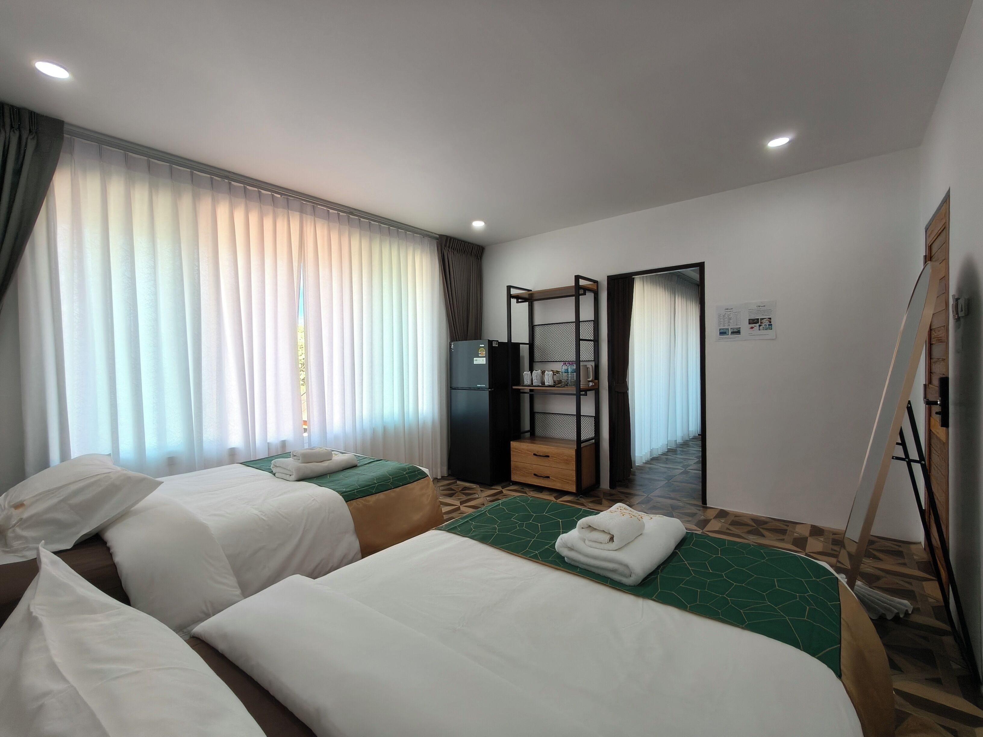 Habitación de hotel con dos camas, un armario, un refrigerador y un baño visible a través de una puerta.
