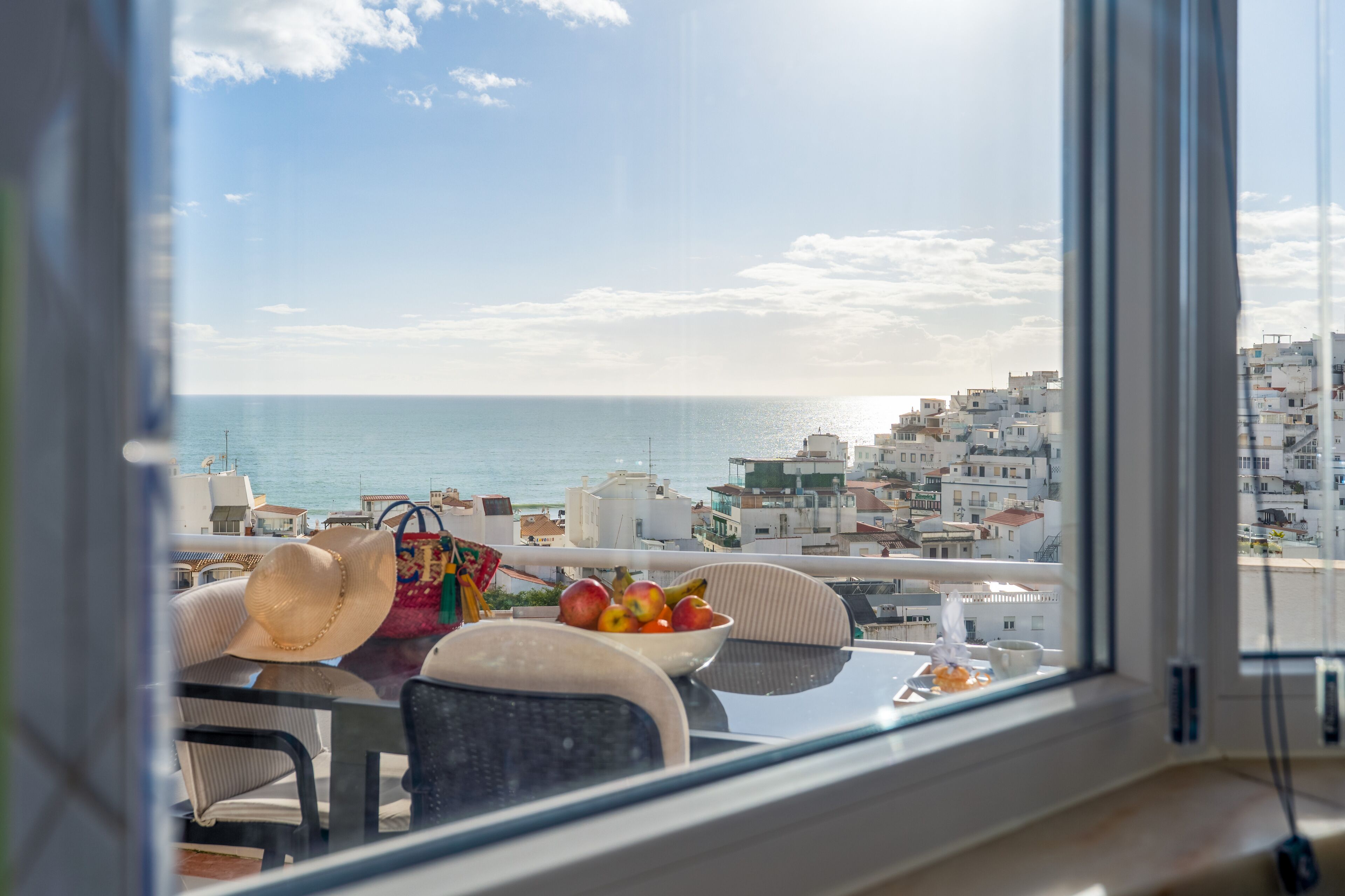 Un balcón con una mesa, sillas y vista al mar y edificios.
