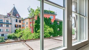 A view from a window overlooking colorful buildings with a clear sky. - Blueground | Zurich town hall, city view, nr Rathaus (Zurich)