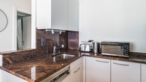 A modern kitchen with granite countertops, a built-in dishwasher, a toaster, a kettle, and a microwave. - Blueground | Zurich town hall, city view, nr Rathaus (Zurich)