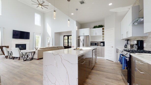 A modern kitchen with white cabinetry, a marble island, and a built-in oven. - Waterfront Retreat Getaway with Gameroom Firepit Fishing Kayaks (Dickinson)