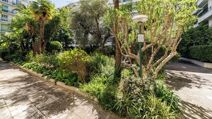 A landscaped courtyard with a variety of plants, a palm tree, and a street lamp.