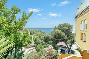 A coastal residential area with Mediterranean architecture, including terracotta roofs and stucco walls, overlooking the sea.