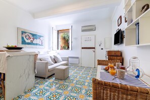 A modern living room with a sofa, a dining table with breakfast items, a TV, and a decorative wall piece.