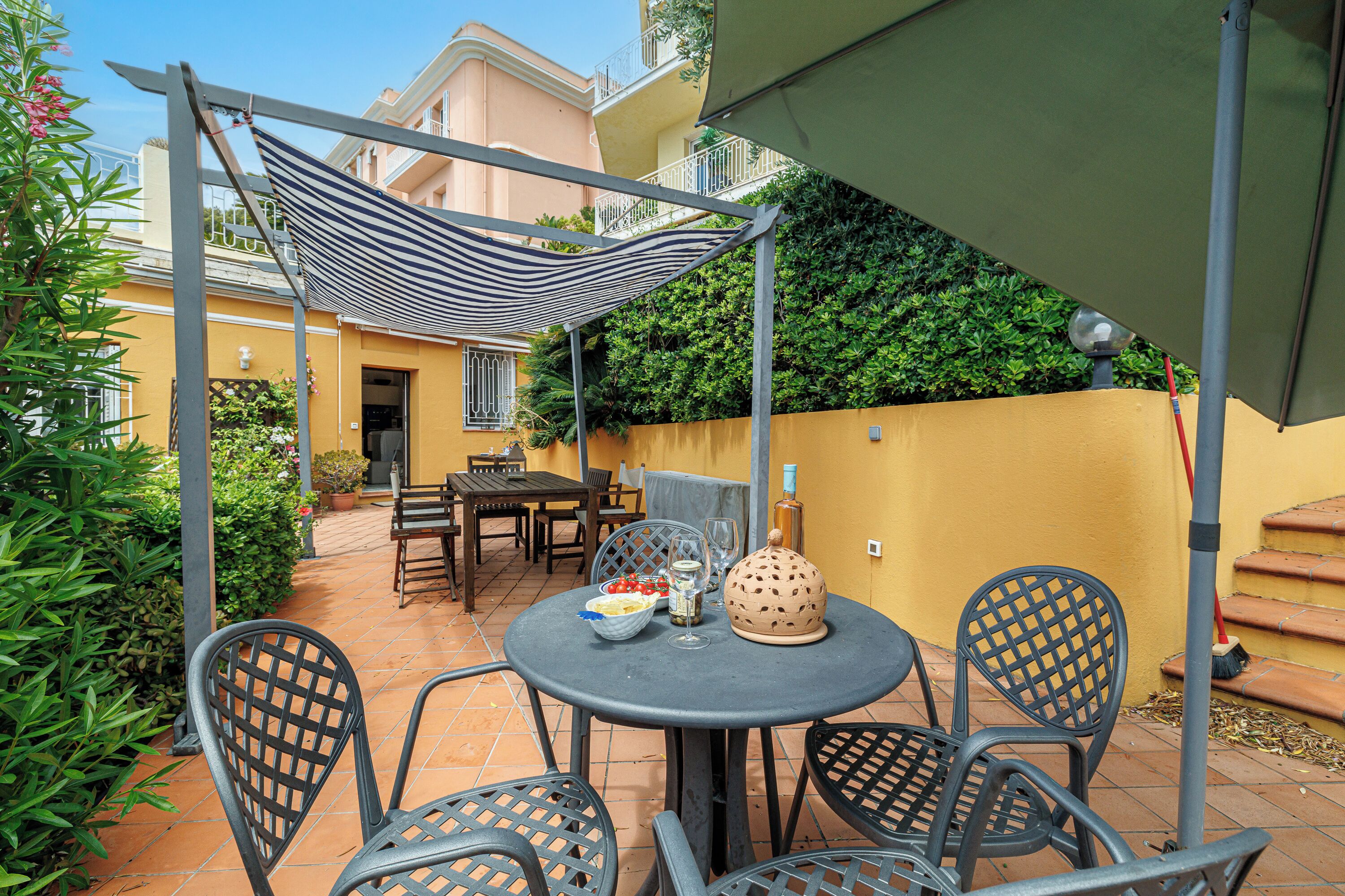 Eine Terrasse mit Tisch, Stühlen und einem Streifen-Sonnenschirm.