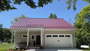 Een gelijkvloers huis met een rood dak, een overdekte veranda en een garage.