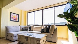 Un salon avec un canapé, une table basse et une grande fenêtre donnant sur un beau paysage.
