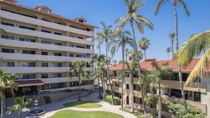 Un hôtel à plusieurs étages doté de balcons, de palmiers et d’une cour intérieure.