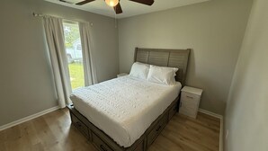 A bedroom with a wooden bed, white bedding, a nightstand, and a ceiling fan. - 2 Bedroom Hideaway in Jacksonville (Jacksonville)