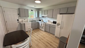 A modern kitchen with grey cabinets, a black countertop, and a wooden floor. - 2 Bedroom Hideaway in Jacksonville (Jacksonville)