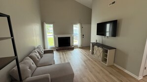 A spacious living room with a fireplace, a large TV, and a sliding glass door leading to a balcony. - 2 Bedroom Hideaway in Jacksonville (Jacksonville)