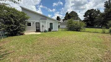 A single-story house with a front porch, a small front yard, and a chain-link fence.