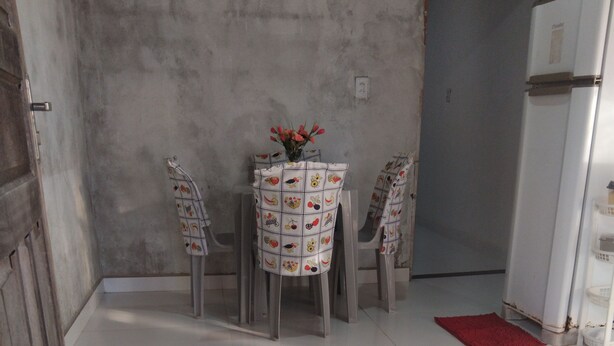 A small, tiled room with a white table and chairs, a red rug, and a refrigerator.