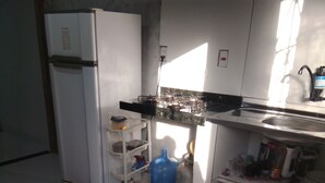 A kitchen with a refrigerator, stove, sink, and various kitchen items.