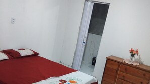 A bedroom with a bed, a dresser, a mirror, and a door.