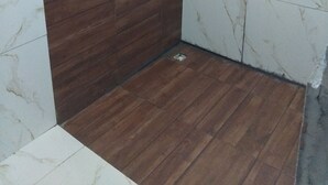 A shower area with a wooden panel wall and white marble tiles.