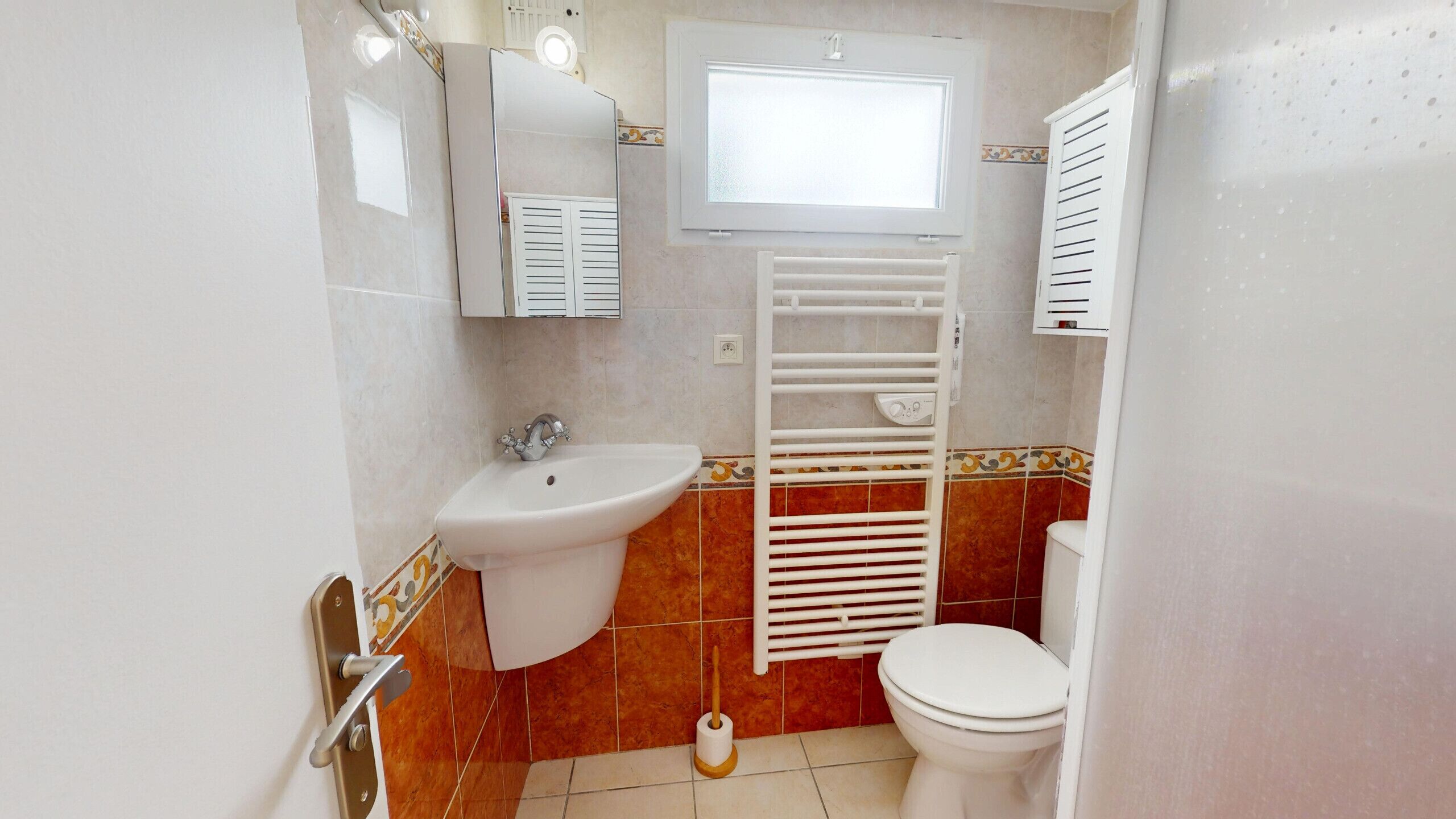 A compact bathroom with a sink, toilet, and a window above the toilet.
