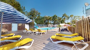Un espace aménagé au bord de la piscine, avec des chaises longues, une piscine et une terrasse en bois.