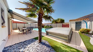 Une terrasse extérieure moderne avec une piscine, un espace salon couvert et un palmier.