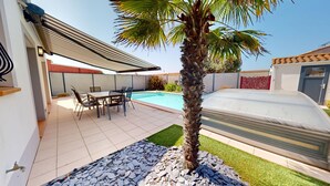 Une terrasse extérieure moderne avec une piscine, un espace salon couvert et un palmier.