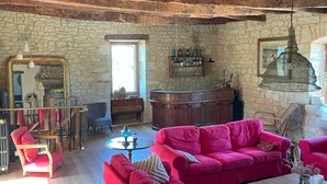 A rustic living room with wooden beams, a stone wall, and a large red sofa.