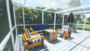 A covered outdoor deck with wooden furniture, including a sofa and chairs, and a small table.