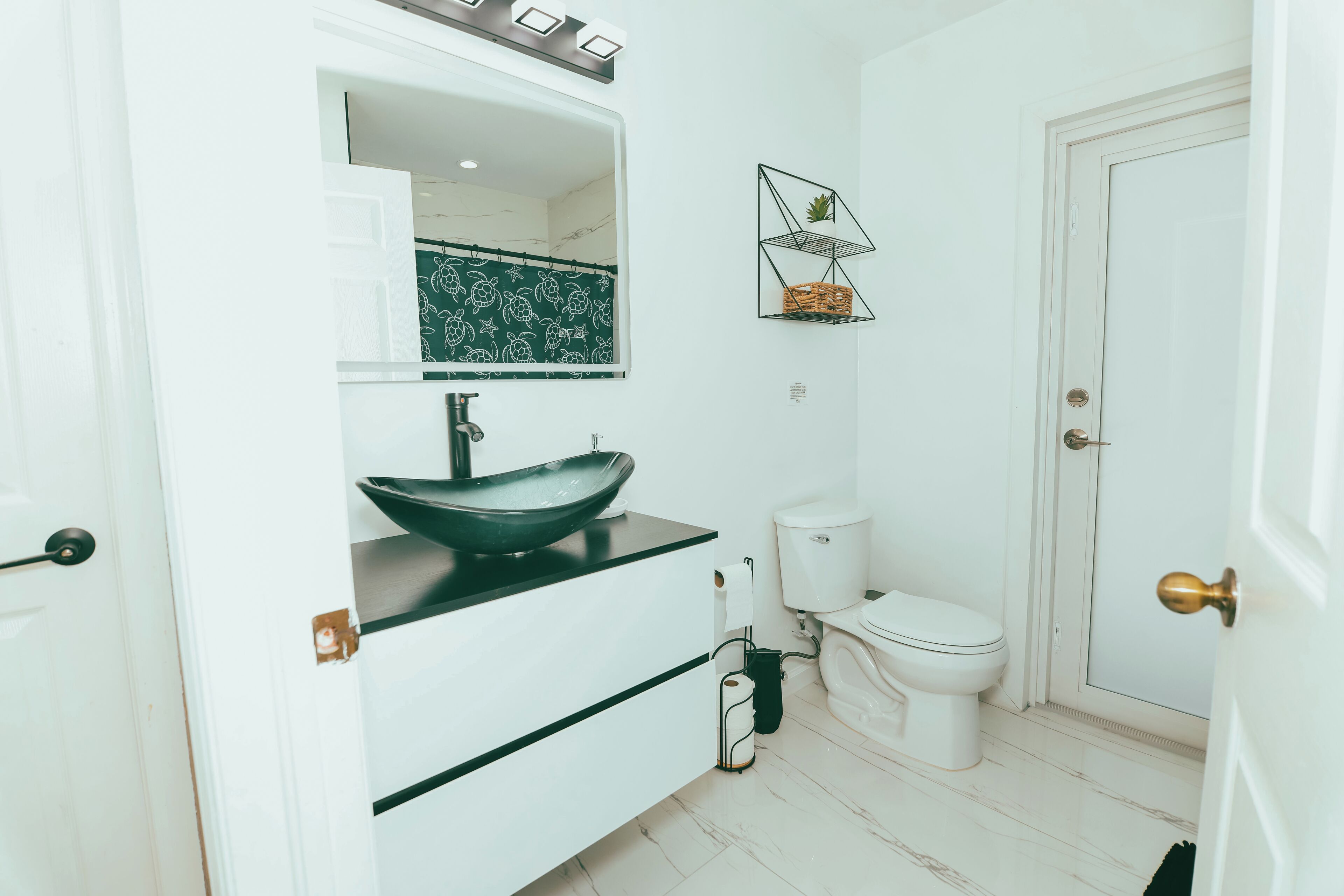 Ein modernes Badezimmer mit einem weißen Waschbecken, einem großen Spiegel und einer Toilette.