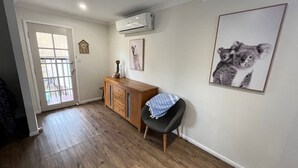 A room with a wooden cabinet, a black chair with a striped cushion, and a koala artwork on the wall.