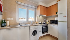 A modern kitchen with a washing machine, oven, microwave, and a refrigerator. - Cabanas Gardens, 4px, Penthouse (Cabanas de tavira)