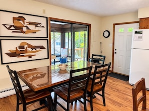 A dining area with a wooden table and chairs, framed artwork on the wall, a clock, and a refrigerator. - Spacious Cabin/Hottub/firepit/Gameroom/Ski Hill/in locust lake (Pocono lake)