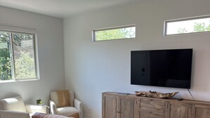 Una sala moderna con un sofá marrón, un televisor y un mueble de madera.