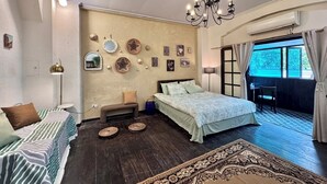 A bedroom with a bed, bedside tables, a bench, a chandelier, and a view of the outdoors.