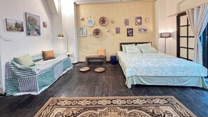 A bedroom with a bed, a sofa, a bench, and a chandelier.